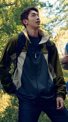 a young man standing in the woods looking up