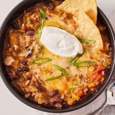 a bowl filled with chili, beans and tortilla chips on top of a table