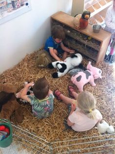 three children sitting in hay with stuffed animals