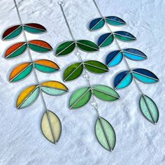 multicolored leaves are hanging from a chain on a white sheet with snow in the background