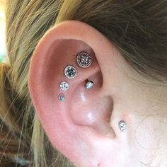 a close up of a person's ear with three different piercings on it