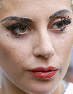 a close up of a woman with makeup on her face and eyeliners, looking at the camera