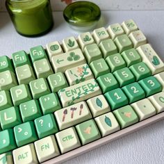 a computer keyboard sitting on top of a table next to a jar of green liquid