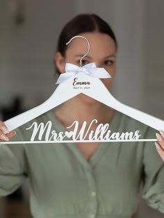 a woman holding up a white hanger with the word mrs williams on it