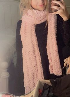 a woman is taking a selfie with her cell phone while wearing a pink scarf