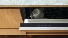 an open dishwasher in a wooden cabinet