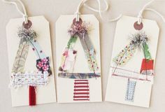 three tags with different designs on them hanging from twine strings, each decorated with ribbons and thread