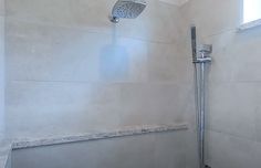 a shower head in a bathroom with white walls and tile flooring, along with a window