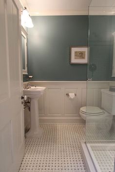 a white toilet sitting next to a sink in a bathroom on top of a tiled floor