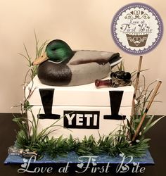 a duck sitting on top of a cake in the shape of a boat and reeds