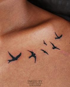 a woman's back with birds flying in the sky on her stomach, inked by vikram