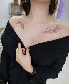 a woman with a leaf tattoo on her chest and shoulder is looking at the camera