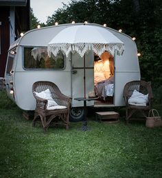 an old camper trailer is decorated with lights and wicker furniture for outdoor seating