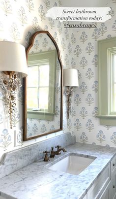 a bathroom sink sitting under a large mirror next to a wall mounted faucet