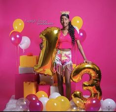 a woman standing in front of balloons and presents with the number 3 on it's side