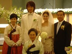 a group of people standing next to each other in front of a table with flowers on it