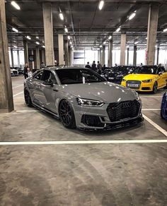 two cars parked in a parking garage with people looking at them from the other side