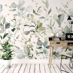 a desk and chair in front of a wall with leaves painted on it