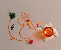 a small candle is sitting next to a drawing on the table that says happy diwali