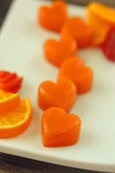 sliced oranges and strawberries on a white plate with hearts cut in the middle