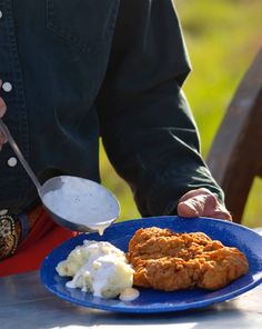 a blue plate topped with fried chicken and mashed potatoes