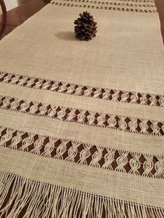 a pine cone is sitting on top of a table cloth with fringes and crochet