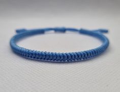 "Light Blue Lucky Knot Bracelet made from nylon cord. This knotted bracelet is designed for both genders males and females. *Size  S - Fully Closed - 5.9\"inches (15cm) / Full Opened - 9.8\"inches (25cm) M - Fully Closed - 6.6\"inches (17cm) / Full Opened - 10.6\"inches (27cm) L - Fully Closed - 7.4\"inches (19cm) / Full Opened - 11.4\"inches (29cm) Made from 1mm nylon cord. - - - - - - - - Blue colors benefits in a spiritual way: - Serenity and Tranquility: Light blue represents a sense of calmness, peace, and tranquility. It brings to mind clear skies and serene oceans, creating a harmonious atmosphere. - Spirituality and Divinity: Blue is connected to the spiritual realm, symbolizing higher states of consciousness and divine connection. It represents wisdom, truth, and spiritual enlight Blue Nylon Cord Friendship Bracelet As Gift, Minimalist Blue Braided Bracelet For Friendship, Blue Nylon Cord Friendship Bracelets As Gift, Blue Sliding Knot Friendship Bracelets In Nylon Cord, Handmade Blue Nylon Cord Friendship Bracelets, Blue Nylon Cord Friendship Bracelets With Sliding Knot, Blue Sliding Knot Friendship Bracelet With Nylon Cord, Minimalist Blue Braided Friendship Bracelet, Blue Minimalist Braided Friendship Bracelet