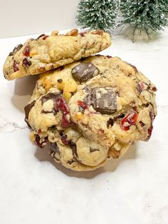 two chocolate chip cookies stacked on top of each other next to a small christmas tree