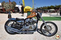 a motorcycle is parked on the gravel at an outdoor event