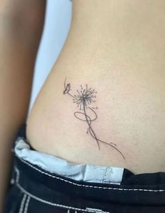 a woman's stomach with a dandelion tattoo on her side ribcage