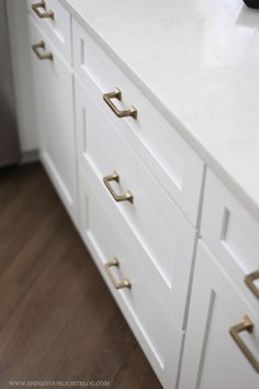 a white dresser with gold handles and drawers in a home office area or kitchen space