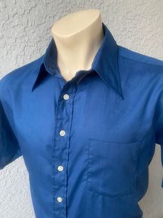 "This deep blue, genuine 1970s vintage, short sleeve, butterfly collared shirt is in excellent vintage condition. SIZE: Pit to Pit: 25\" Collar to hem: 31\" Sleeves: 11\" The tag does not have a size. Check the measurements. I would say it fits like a roomy XL The male mannequin would be 5'10\" 170 lbs. ITEM 125" Fitted Collared Short Sleeve Shirt For Summer, Blue Semi-formal Summer Shirt, Blue Short Sleeve Shirt With Spread Collar For Summer, Blue Polo Collar Top For Formal Occasions, Blue Fitted Cotton Short Sleeve Shirt, Fitted Blue Cotton Short Sleeve Shirt, Blue Formal Polo Collar Top, Solid Vintage Summer Shirt, Formal Blue Polo Collar Top