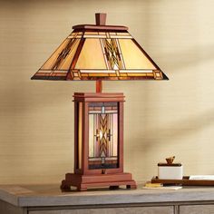 a lamp sitting on top of a wooden table next to a desk with a drawer