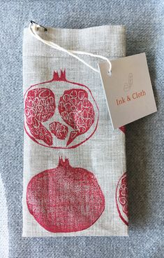 a red and white bag with an ornament on it next to a tag that says ink & cloth