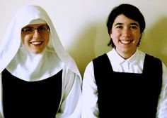 two women dressed in nun costumes standing next to each other, smiling at the camera