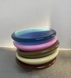 a stack of multicolored bowls sitting on top of each other in front of a white wall