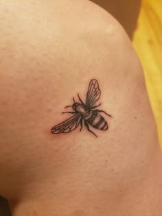 a small black and white bee tattoo on the back of a woman's stomach