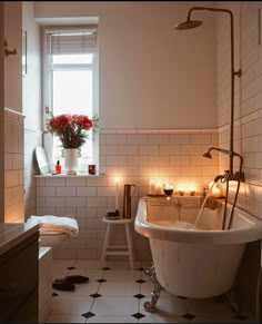 a bath tub sitting next to a window with candles on the wall and in front of it