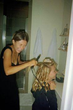 a woman blow drying her daughter's hair in the bathroom