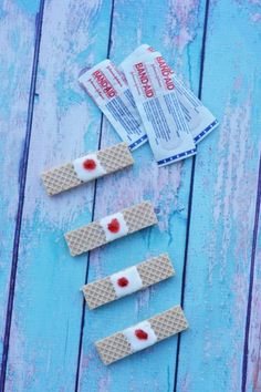 three waffles with candy on them sitting on a blue wooden table next to two packets of toothpaste