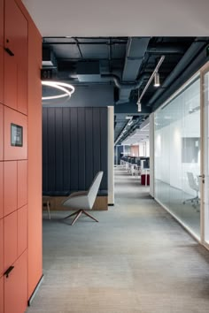 an empty office with red walls and white chairs in the center, along with glass partitions