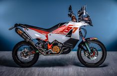 a white and red dirt bike parked on top of a wooden floor next to a blue wall