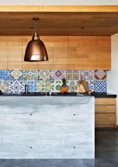 a kitchen with wooden cabinets and tile backsplash in the center, along with copper pendant lights