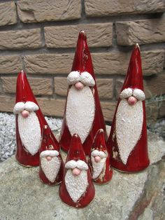 a group of red santa claus figurines sitting on top of a stone wall