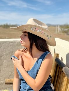 Introducing The Katie Lou—a tribute to delicate beauty and untamed spirit. Handcrafted from luxurious, sustainable Australian wool, The Katie Lou showcases an intricate array of delicate wildflowers, adding a touch of nature’s splendor to its classic cowboy shape. The artistic detailing creates a romantic, ethereal aesthetic perfect for those who live unapologetically free. With every stitch and brushstroke, this hat captures the essence of "spirits by the fire"—perfect for bonfire nights, count Adjustable Country Style Felt Hat For Summer, Summer Brimmed Felt Hat For Rodeo, Western Felt Hat With Short Brim For Summer, Curved Brim Summer Felt Hat For Rodeo, Western Style Felt Hat With Short Brim For Summer, Summer Rodeo Brimmed Felt Hat, Summer Felt Hat With Curved Brim For Rodeo, Summer Felt Hat For Rodeo With Brim, Natural Color Hat Bands For Rodeo In Spring