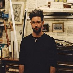 a man standing in front of an old typewriter with lots of papers on the wall behind him