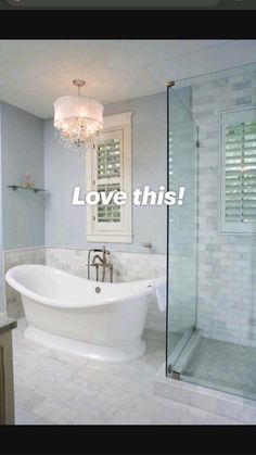 a white bath tub sitting under a chandelier next to a walk in shower