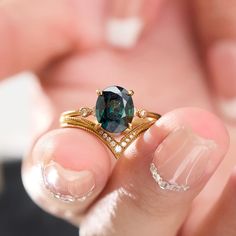 a close up of a person holding a ring with a blue stone in the middle