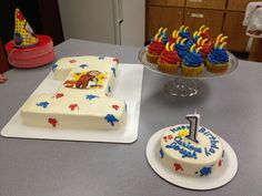 a birthday cake and cupcakes on a table