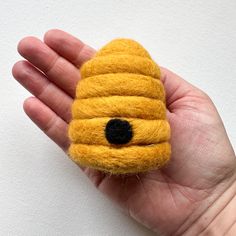 a hand holding a small yellow object with a black eye on it's face